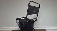 Side view of black camping chair with Xbox logo on backrest, attached black cooler bag beneath seat and armrest cup holder.