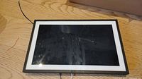 Full front view of Amazon Echo Show 15.6-inch smart display lying face up on wooden surface.