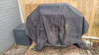 Black protective cover over the BBQ grill, shows dirt and use