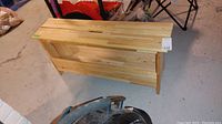 Front and top view of a wooden bench showing the top surface and front panel, highlighting the wood grain and finish.
