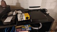 Wide view of the lot showing ZTE router, yellow and white projector, hard drive, cables, and damaged device.