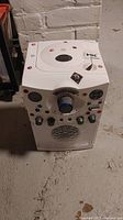 Front view of the white Singing Machine Karaoke Machine with colorful buttons, speaker grille, and microphones.