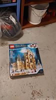 Photo of the unopened LEGO Harry Potter Hogwarts Clock Tower set box placed on the floor, showing the front with images and branding.