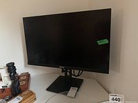 Full front view of monitor on stand with power cable coiled, dusty surface visible
