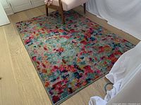 Full view of rug on light wood floor with partial chair visible