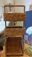 Full view of woven shelving unit showing three basket shelves and handle