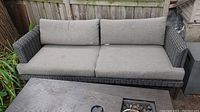 Full view of the outdoor faux wicker sofa with two seat cushions and two back cushions. Sofa fabric cushions are stained.