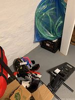 Hockey skates, two baseball catcher's mitts, and a black metal stand inside basement corner