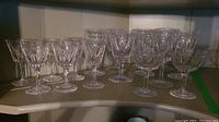 Photo showing all 16 crystal glasses grouped on a shelf: eight large wine glasses, six sherry glasses, two champagne glasses.