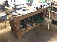 Overall view of wooden workbench with assorted hardware, organizer bins, and tools on top and on lower shelf