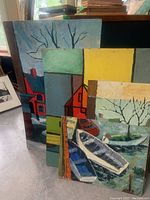 Four oil paintings leaning against each other showing portion of abstracted houses and boats, illustrating lot contents.
