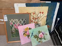 Photo showing the five oil paintings on canvas boards, one framed, with floral motifs and varying sizes.