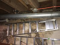 Full view of the 8 step aluminum ladder laid horizontally in a basement area, showing overall length and step spacing.