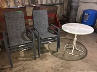 Two stackable sling chairs next to the white metal mesh top outdoor table.