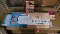 Photo showing Wii Sports game box with original packaging and accessories compartment visible.