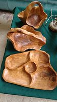 Three wooden bowls displayed on a green cloth, showing natural wood grain and carved details