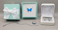 Photo of all jewelry items including turquoise gift box with bow containing necklace, white box containing earrings, ring with turquoise inlay, and silver bracelet chain.