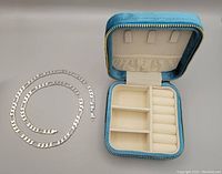 Sterling silver chunky chain necklace laid out next to the blue lined jewelry storage box, showing chain length and box interior compartments
