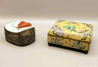 Two vintage Chinese boxes: cloisonne rectangular box with butterfly design and porcelain trinket box with fish lid, displayed together.