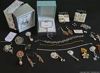 Photo showing assorted costume jewellery including necklaces, earrings, bracelets, pendants in mixed metals with some pieces laid out beside coin and ruler for scale