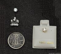 Close-up photo showing the yellow gold star stud, the white gold crown belly button piece with cubic zirconia, and a Canadian dime for size reference.