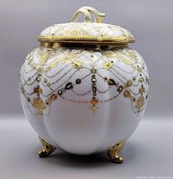 Front view of the Noritake Nippon jar showing gold and colored hand-painted designs and gold feet.
