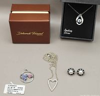 Full lot with two boxed necklaces, one heart necklace with chain, hummingbird pendant necklace with tag, and pair of pearl stud earrings.