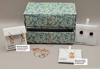 Full lot including a decorative two-drawer box and all four jewelry items displayed on white cards with tags.