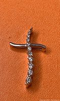 Front view of the 14K white gold cross pendant showing diamonds and the missing top stone.