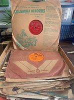 Stack of vintage 78 RPM records in original paper covers showing Columbia Records sleeve on top