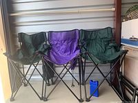 Three folding chairs (two green, one purple) with one blue freezer pack placed in front of them