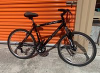 Full left side view of black and gold Columbia Trailhead mountain bike, showing frame, tires, wheels, saddle, and handlebars.