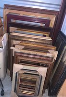 Grouped assortment of over 20 gallery frames stacked vertically, showing wood, silver, gold, and crackled finishes