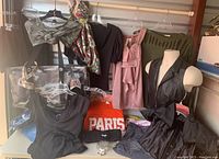 Multiple junior size ladies clothing items including tops, dresses, jeans, shorts, leather vest, scarf, and a camouflage bag with more clothes inside.
