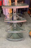 Front view of modern media stand with four curved tempered glass shelves and metallic grey frame.