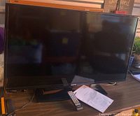 Photo of the Samsung 40 inch LED TV powered off on a surface showing the front screen and TV stand.