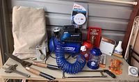 Full lot overview showing air compressor, coping saw, cutters, wrenches, lanterns, drop cloth, smoke alarm, wall art, and other tools.
