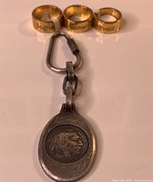 Keychain with attached 1937 Buffalo nickel coin displayed with three gold tone rings with Chinese symbol engravings.