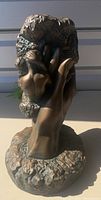 Front angle of the vintage chalkware statue showing the hand holding duo couple sculpture with dark bronze/copper glaze finish on textured base.