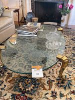 Oval glass top and two gold iron legs visible from angled side view