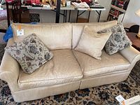 Full view of the gold fine striped couch showing the shape, fabric, and four throw pillows.