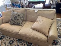 Full view of the gold-striped couch with throw pillows on a floral-patterned area rug.