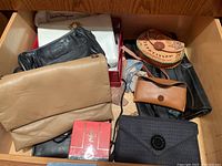 Drawer filled with various handbags, clutches, YSL perfume box, sunglasses case