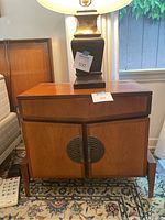 Front right three-quarter view of walnut nightstand with lamp on top.