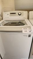 Front view of LG white top-load washing machine with control panel, glass lid, MaxSold lot sticker visible