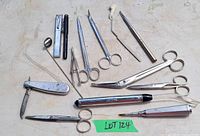 Full view of all vintage medical instruments arranged on surface showing scissors, forceps, knife, scalpel, penlight and other tools