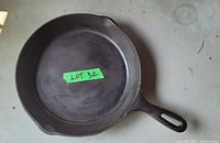 Top view of the 10-inch cast iron frying pan showing the round cooking surface and handle with hole for hanging. Surface has visible patina and discoloration from use.