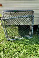 Three metal chain link gates leaning against a trailer showing overall condition and size.