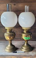 Front view of two English brass Duplex oil lamps with white globes and chimneys, showing different burner and base styles and relative size.