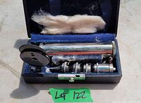Full view of vintage ophthalmology scope inside original blue velvet-lined case with some padding and visible dust.